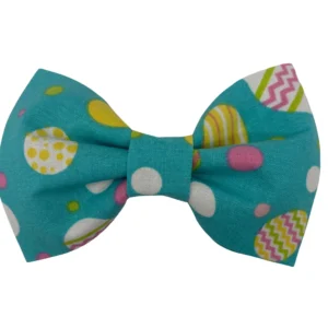 The Eggstra Fancy Pet Bowtie is a teal fabric accessory adorned with polka dots and zigzags in white, yellow, pink, and green. It features various circle sizes and styles, neatly tied for your pets flair.